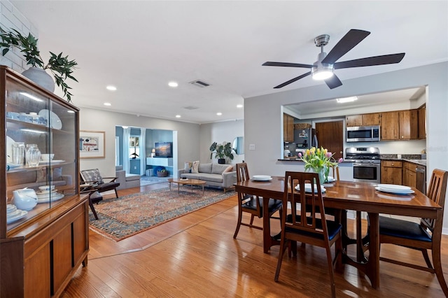 dining area featuring ceiling fan, light wood-style floors, ornamental molding, and recessed lighting