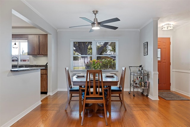 dining area with crown molding, light wood-style flooring, a ceiling fan, and a wealth of natural light