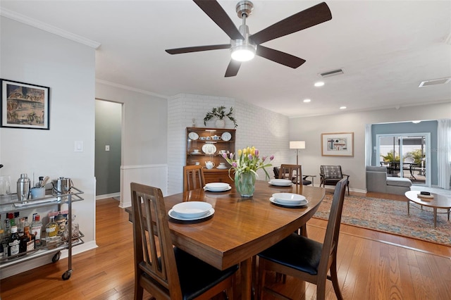 dining room with visible vents, baseboards, ornamental molding, hardwood / wood-style floors, and a ceiling fan