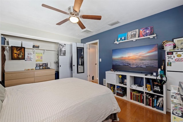 bedroom featuring a closet, visible vents, ceiling fan, and wood finished floors