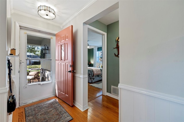 entryway with crown molding, plenty of natural light, visible vents, and light wood finished floors