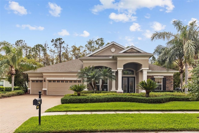 view of front of home with stucco siding, a front yard, an attached garage, and driveway