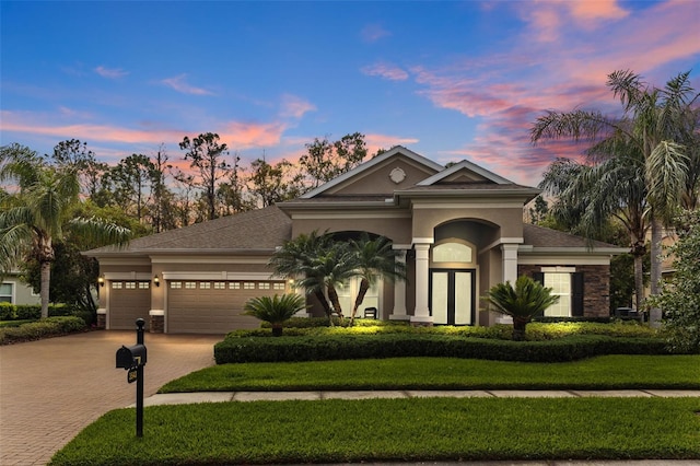 view of front of property featuring a yard, a garage, driveway, and stucco siding