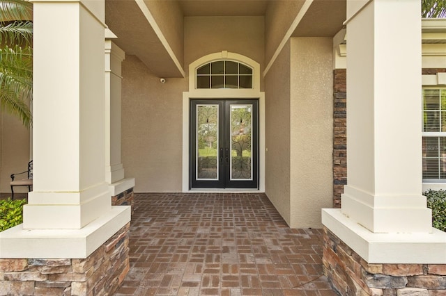 entrance to property with french doors, stone siding, and stucco siding