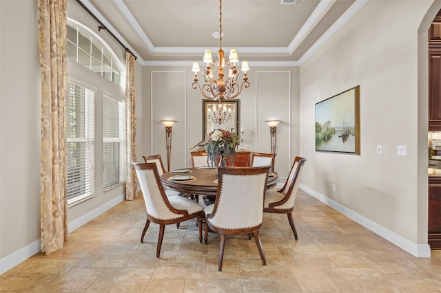 dining room featuring baseboards, an inviting chandelier, a tray ceiling, arched walkways, and crown molding