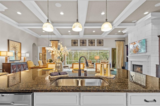 kitchen with a glass covered fireplace, dark stone counters, open floor plan, and a sink