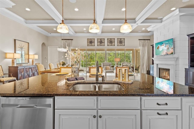 kitchen with open floor plan, white cabinets, dishwasher, and a sink