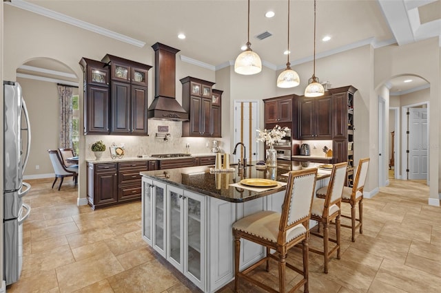 kitchen featuring visible vents, backsplash, premium range hood, appliances with stainless steel finishes, and arched walkways