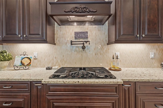 kitchen with tasteful backsplash, dark brown cabinets, black gas stovetop, and custom range hood