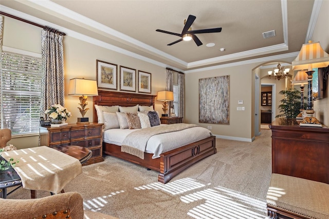 carpeted bedroom with visible vents, crown molding, baseboards, a tray ceiling, and arched walkways