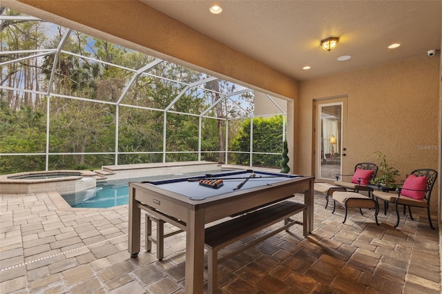 view of patio with glass enclosure and a pool with connected hot tub