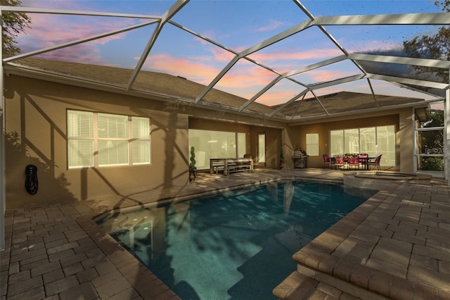 view of pool with a lanai, a pool with connected hot tub, outdoor dining area, and a patio