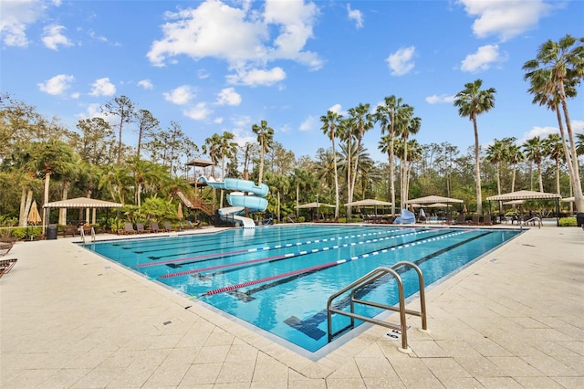 community pool featuring a gazebo, a water slide, and a patio