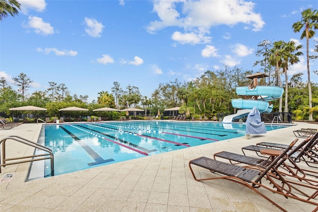 community pool featuring a patio area and a water slide