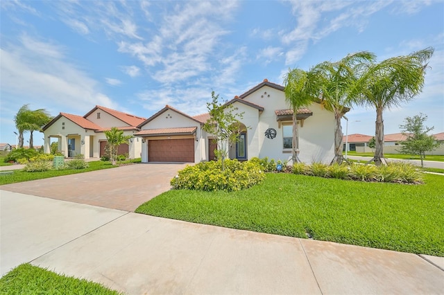 mediterranean / spanish-style home with stucco siding, a front lawn, a tile roof, driveway, and a garage