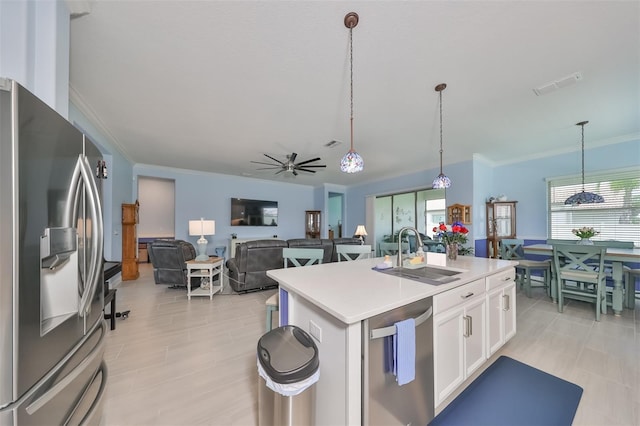 kitchen featuring a sink, stainless steel appliances, light countertops, white cabinetry, and decorative light fixtures