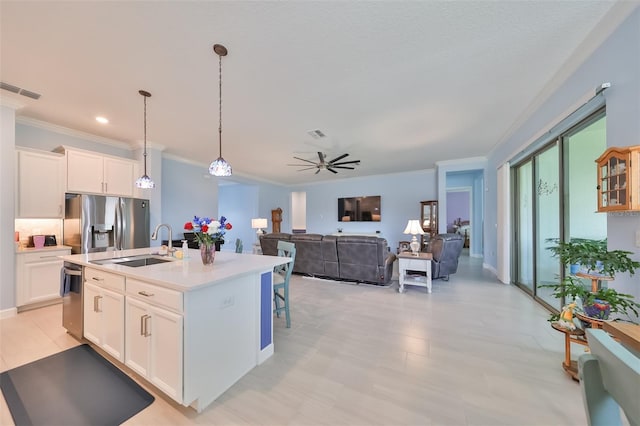 kitchen with a sink, appliances with stainless steel finishes, light countertops, and white cabinetry