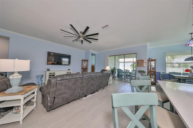 living area with ceiling fan, visible vents, and ornamental molding