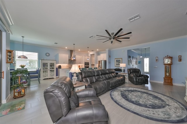 living area with a ceiling fan, crown molding, a healthy amount of sunlight, and visible vents