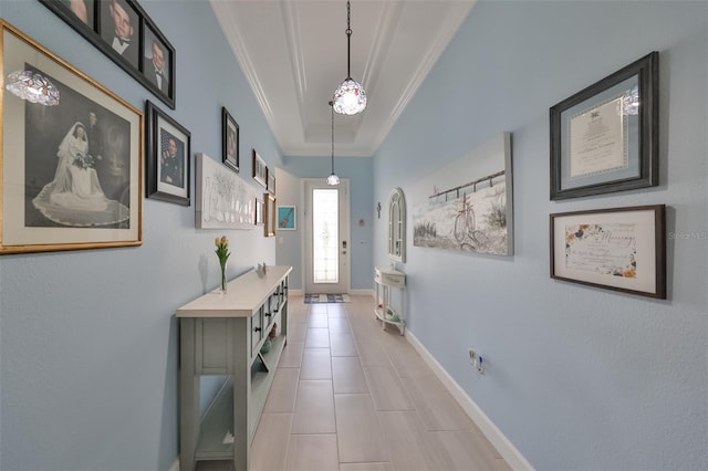 doorway to outside with a raised ceiling, light tile patterned floors, crown molding, and baseboards