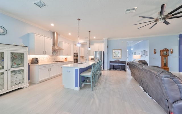 kitchen with wall chimney exhaust hood, visible vents, and open floor plan