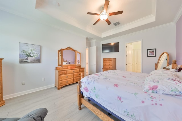 bedroom with a ceiling fan, baseboards, visible vents, a tray ceiling, and ornamental molding