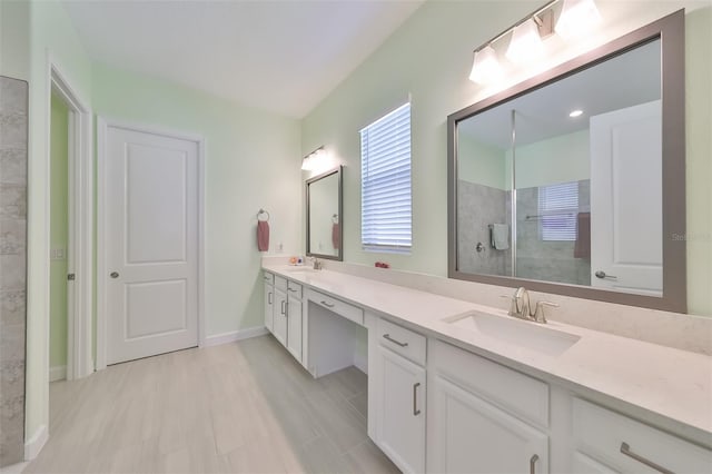 bathroom featuring double vanity, baseboards, a tile shower, and a sink