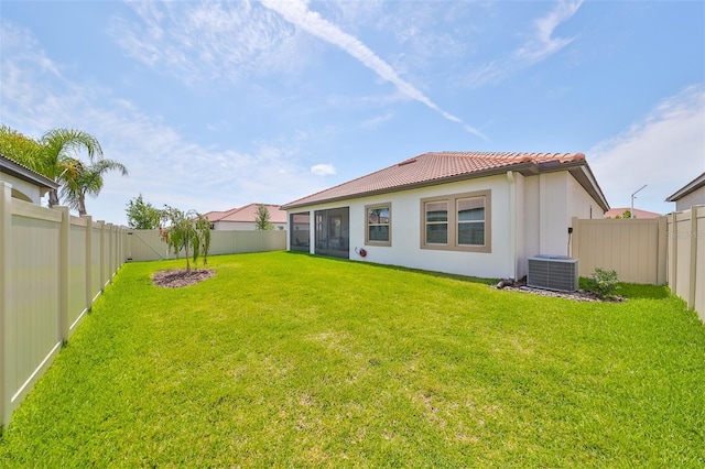 rear view of property with a fenced backyard, stucco siding, a tiled roof, and a yard