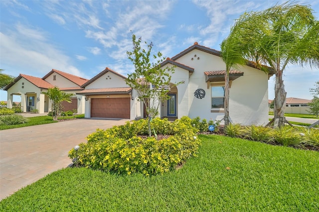 mediterranean / spanish-style house featuring driveway, an attached garage, stucco siding, a front lawn, and a tiled roof