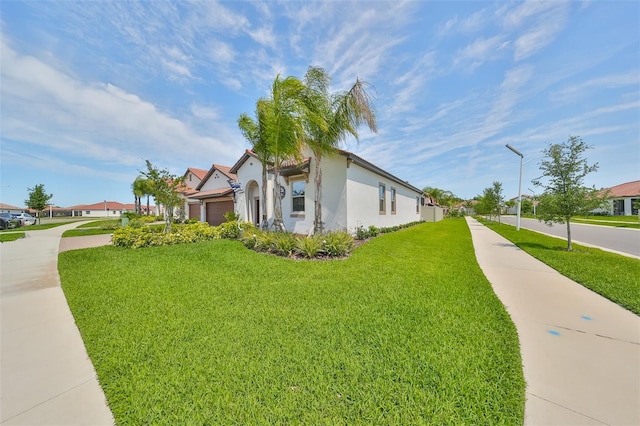 view of property exterior featuring a yard, a garage, concrete driveway, and stucco siding