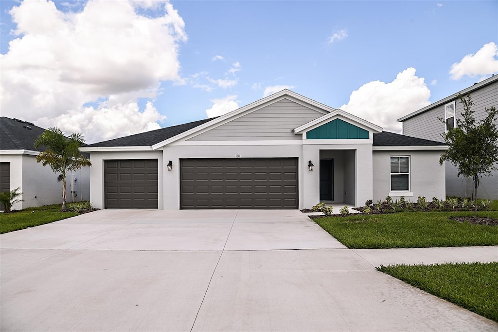 view of front of house featuring a front lawn, an attached garage, and driveway