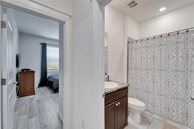 bathroom with a shower with curtain, vanity, toilet, visible vents, and wood finished floors