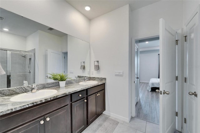 bathroom with double vanity, a sink, a stall shower, and tile patterned flooring