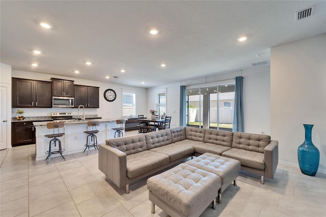 living room with light tile patterned flooring, visible vents, and recessed lighting
