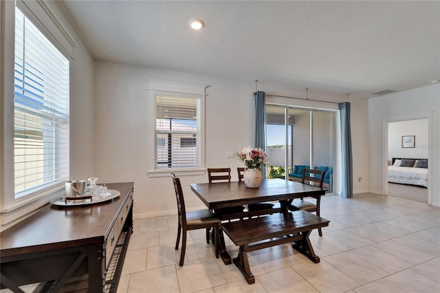 dining space featuring baseboards, visible vents, a textured ceiling, and light tile patterned floors