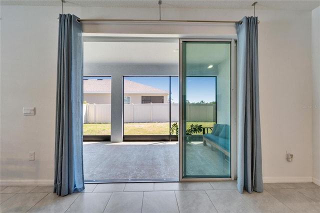 doorway with baseboards and tile patterned flooring
