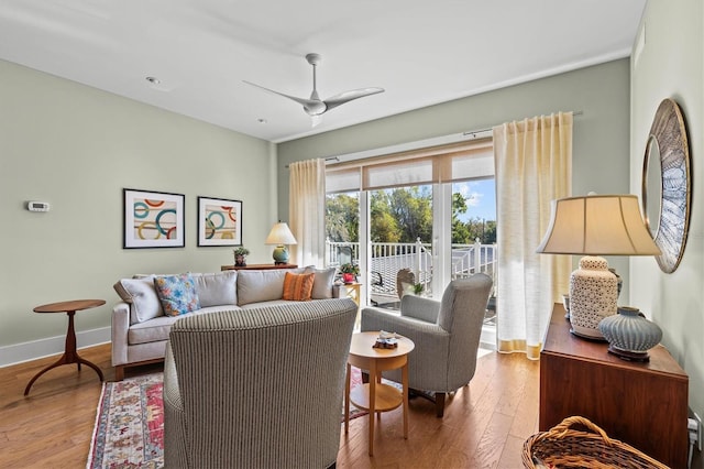 living room featuring baseboards, wood finished floors, and a ceiling fan