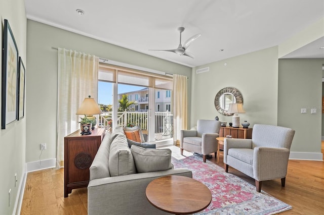 living area featuring visible vents, baseboards, wood finished floors, and a ceiling fan