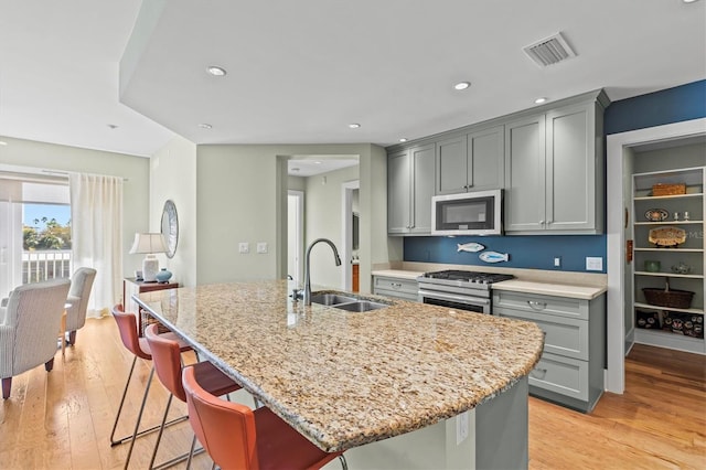 kitchen featuring visible vents, light stone countertops, gray cabinets, appliances with stainless steel finishes, and a sink