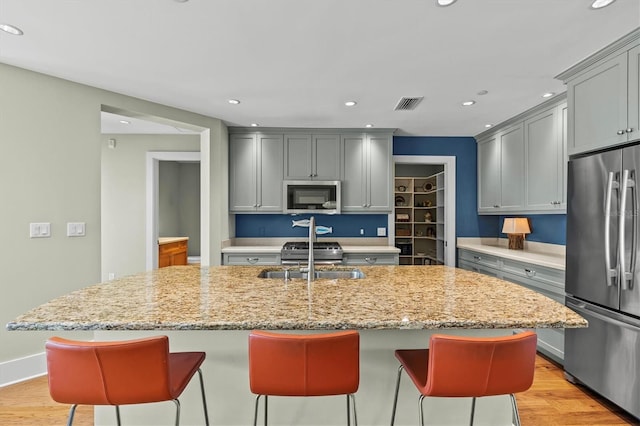 kitchen featuring visible vents, gray cabinetry, a sink, appliances with stainless steel finishes, and light wood-type flooring