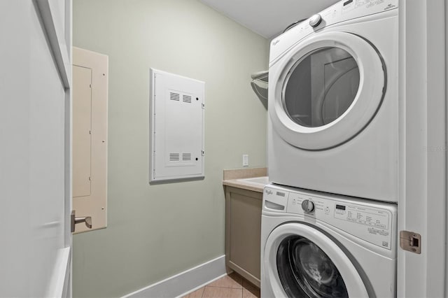 laundry room with light tile patterned flooring, stacked washer and clothes dryer, and baseboards