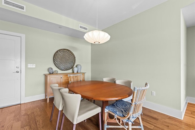 dining space with light wood-type flooring, visible vents, and baseboards