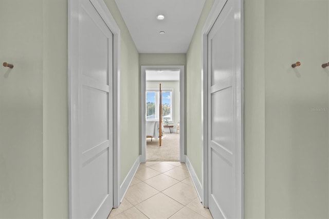 hall featuring light tile patterned flooring and baseboards