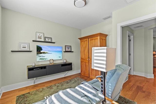 living area with wood finished floors, visible vents, and baseboards