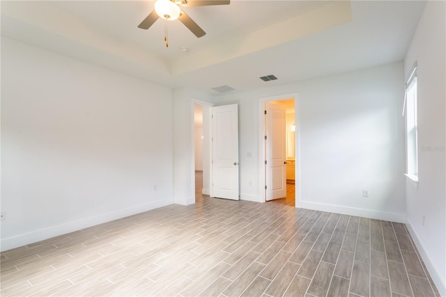 spare room with visible vents, baseboards, light wood-type flooring, and ceiling fan