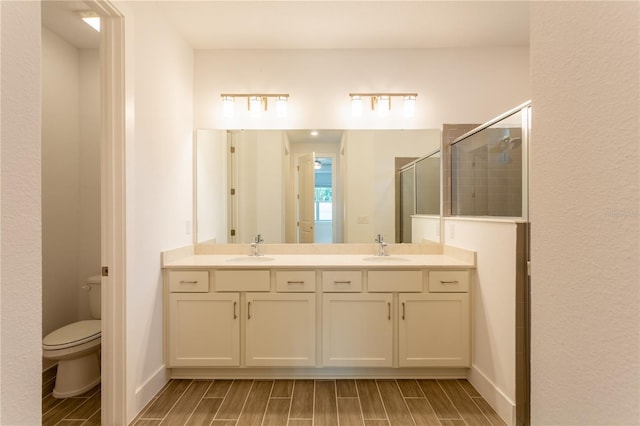 full bathroom featuring a sink, toilet, a stall shower, and wood tiled floor