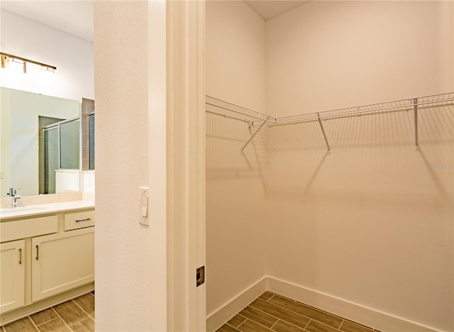 walk in closet featuring a sink and wood tiled floor