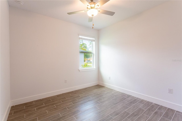 unfurnished room with dark wood-type flooring, a ceiling fan, and baseboards