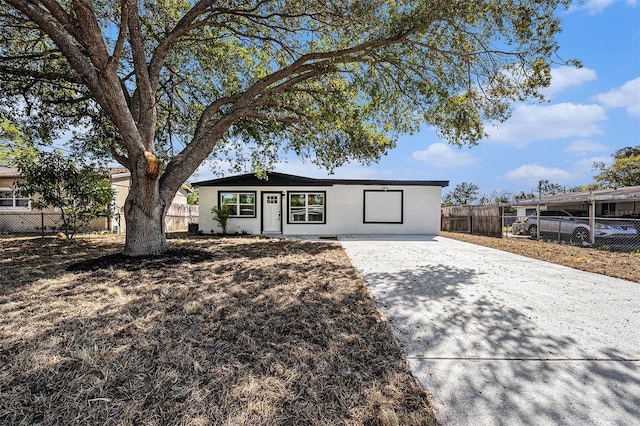 ranch-style house featuring stucco siding, driveway, and fence