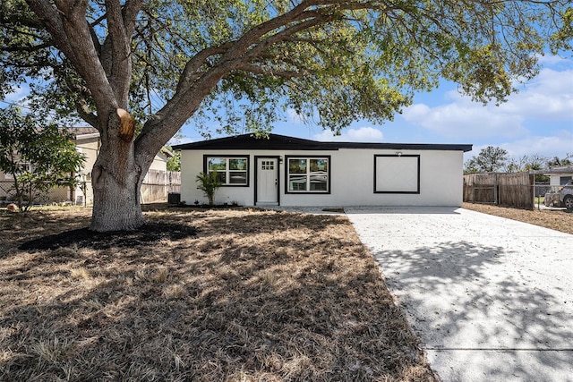 ranch-style home with stucco siding, driveway, and fence